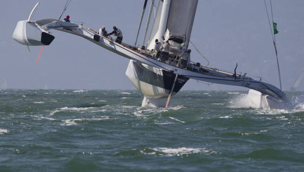 Proa do trimarã cortando o mar em dia de vento forte
