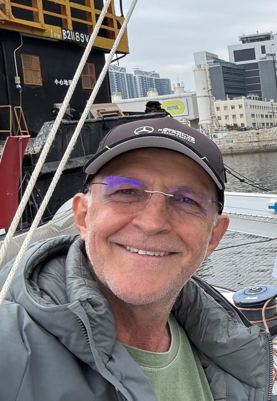 Claudio Cardoso de boné e óculos, sorrindo a bordo do barco